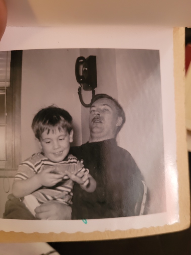 A mustached man holds a smiling child in his arms.
